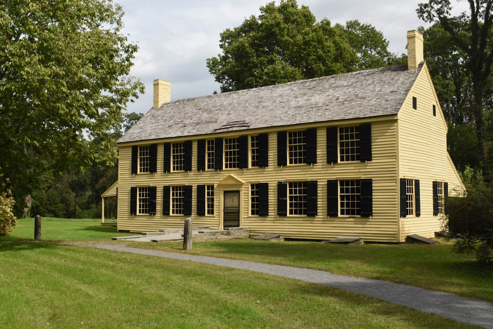 a large yellow house sitting on top of a lush green field