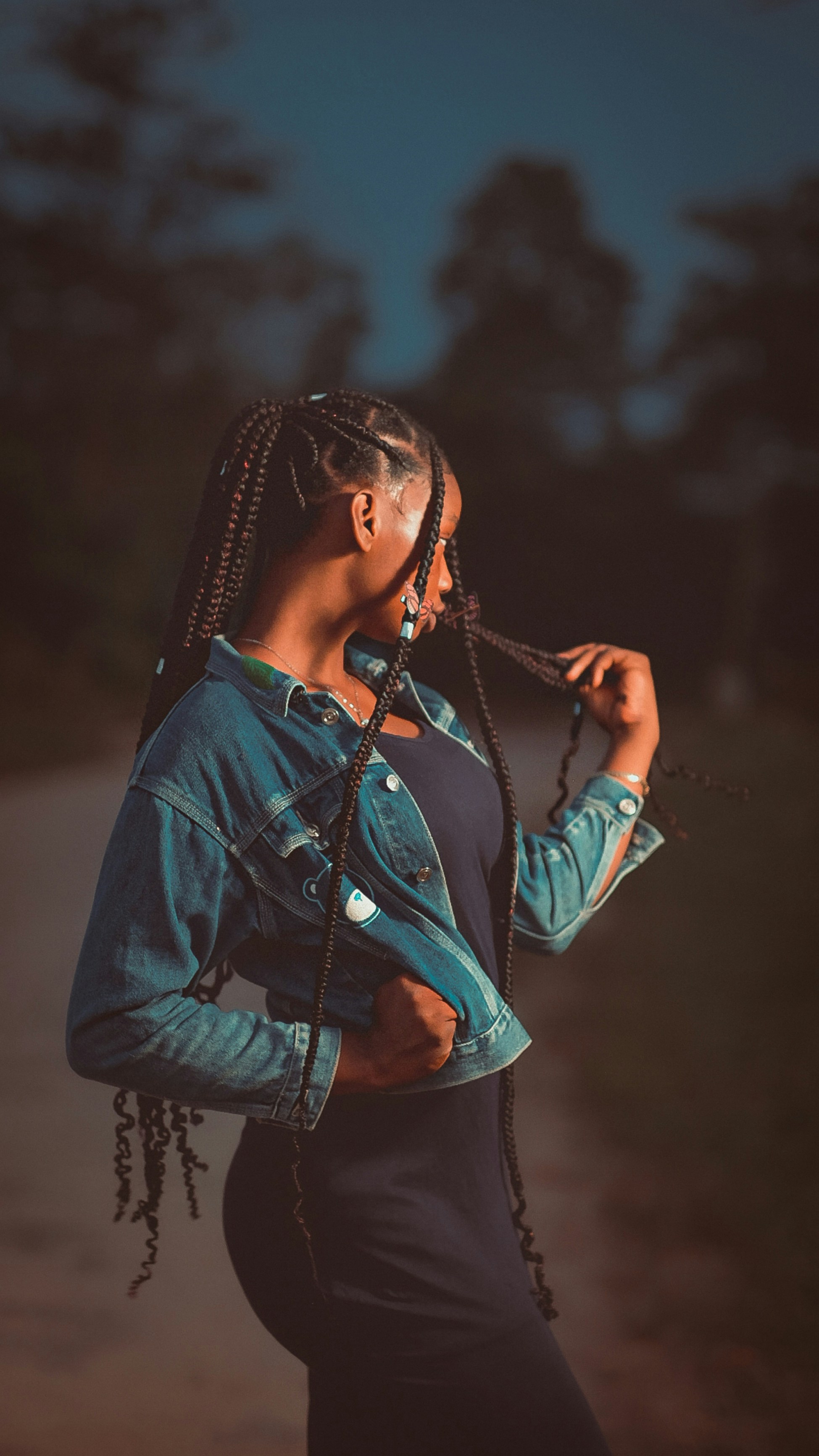 a woman with braids standing on a dirt road