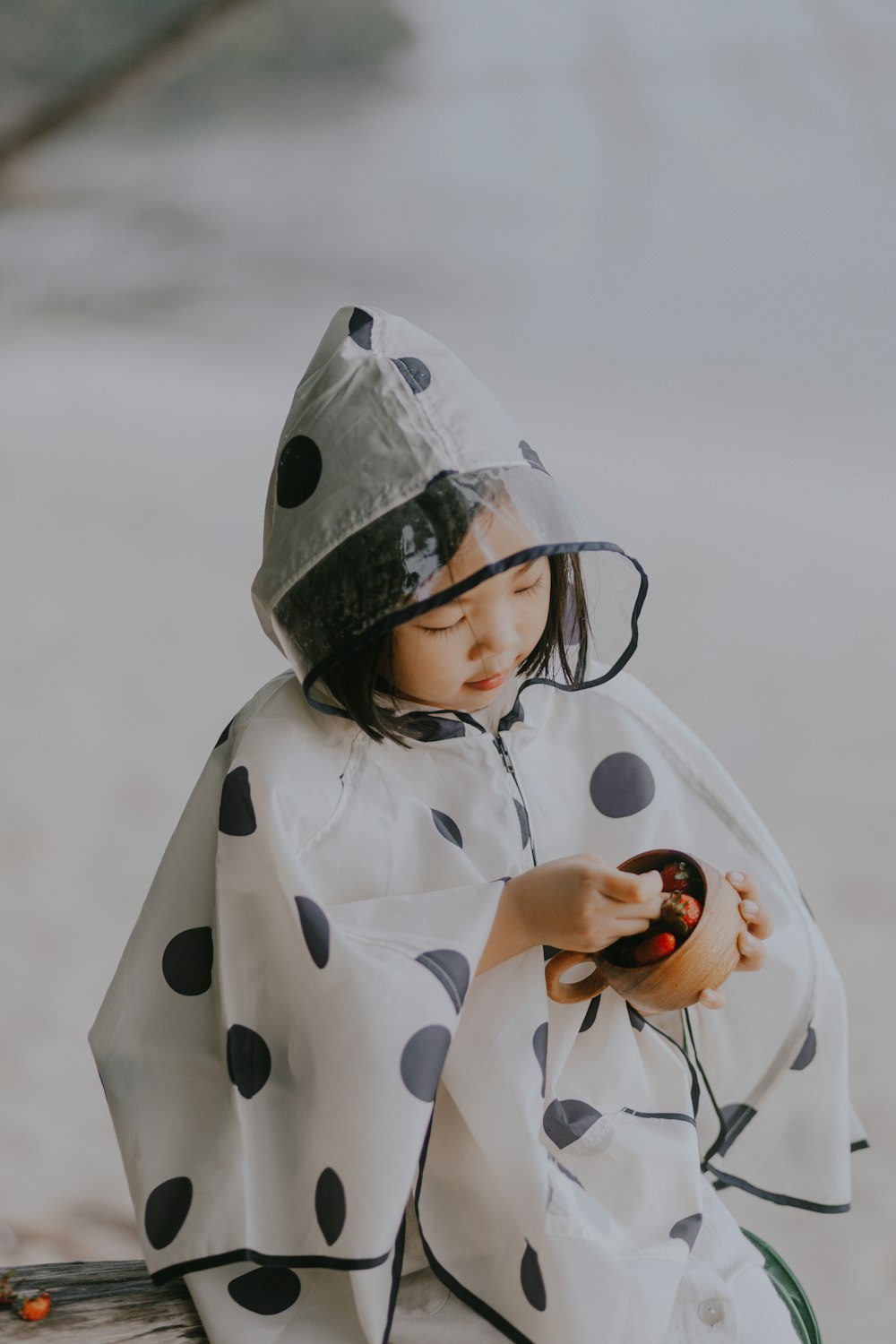 a little girl dressed in a polka dot raincoat