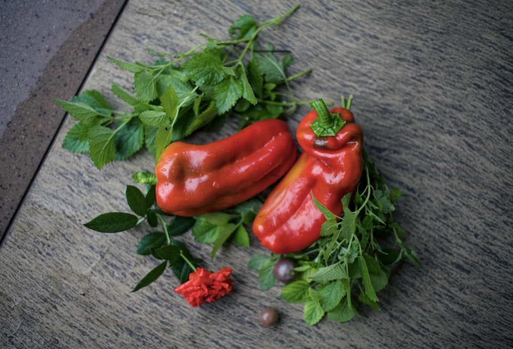 a couple of red peppers sitting on top of green leaves