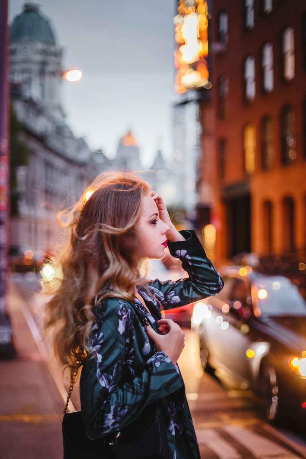 a woman standing on the side of a street next to a car