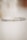 A close-up view of a delicate bracelet made of small, faceted, transparent beads arranged in a circular shape. The background is softly blurred, creating a minimalist and elegant composition.