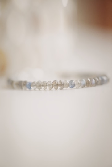 Minimalist photo of a silver bracelet on a white marble background with soft natural light.