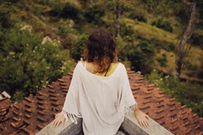 a woman sitting on top of a roof next to a forest