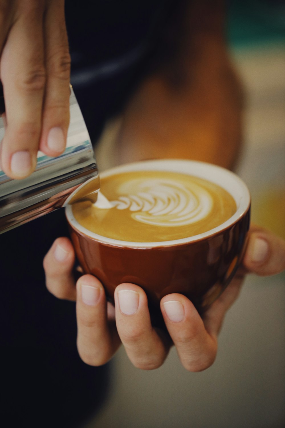 a person pouring a cup of coffee into a cup