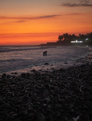 a person riding a surfboard on top of a rocky beach