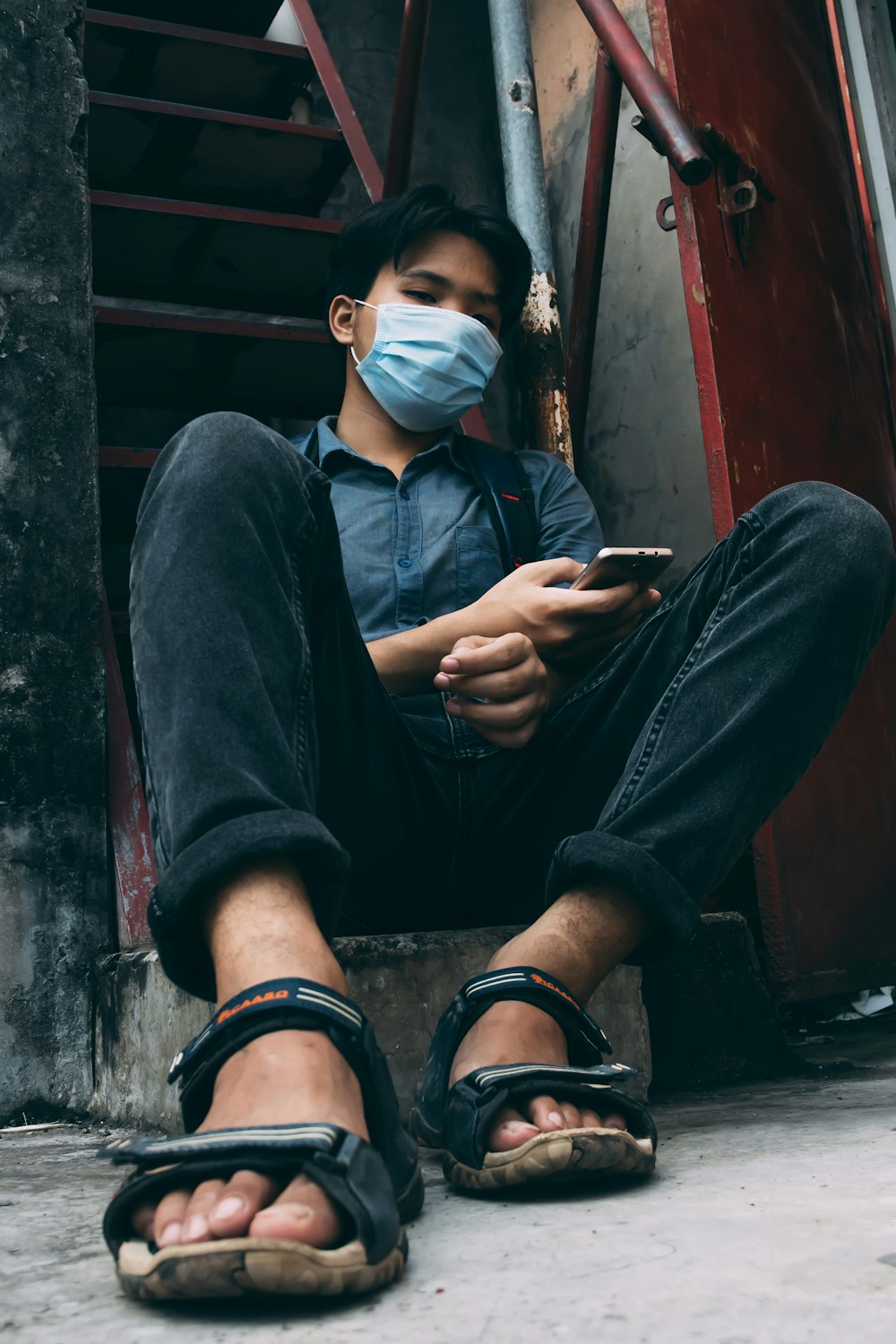 a man wearing a face mask while sitting on the ground