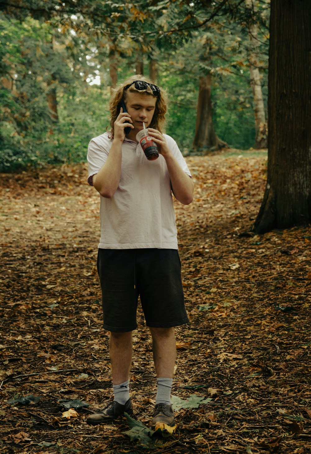 a man standing in the woods talking on a cell phone