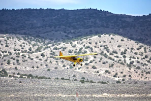 Aerial shot of a small private plane flying over the rugged Santa Fe landscape.