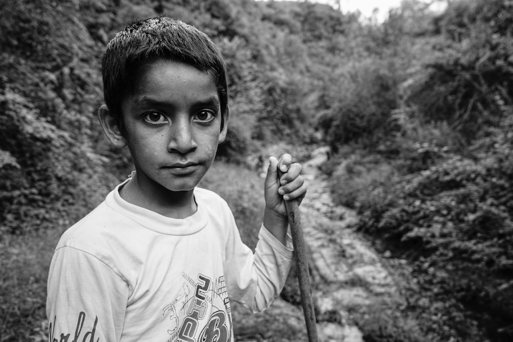 a black and white photo of a young boy holding a stick