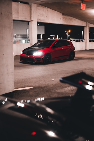 A sleek black luxury car with shiny red accents parked inside a stylish garage.