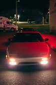 Sporty car with glowing headlights parked in an urban night setting.