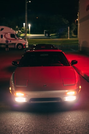 Sporty car with glowing headlights parked in an urban night setting.