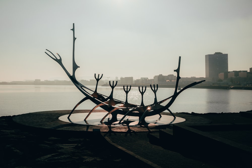 a group of metal sculptures sitting next to a body of water