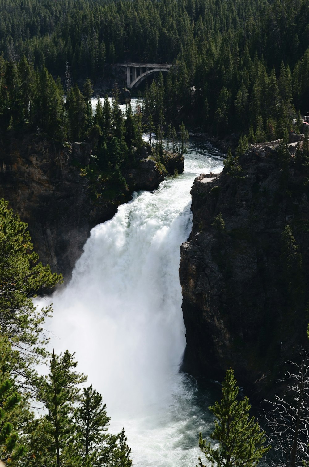 a large waterfall with a bridge in the background