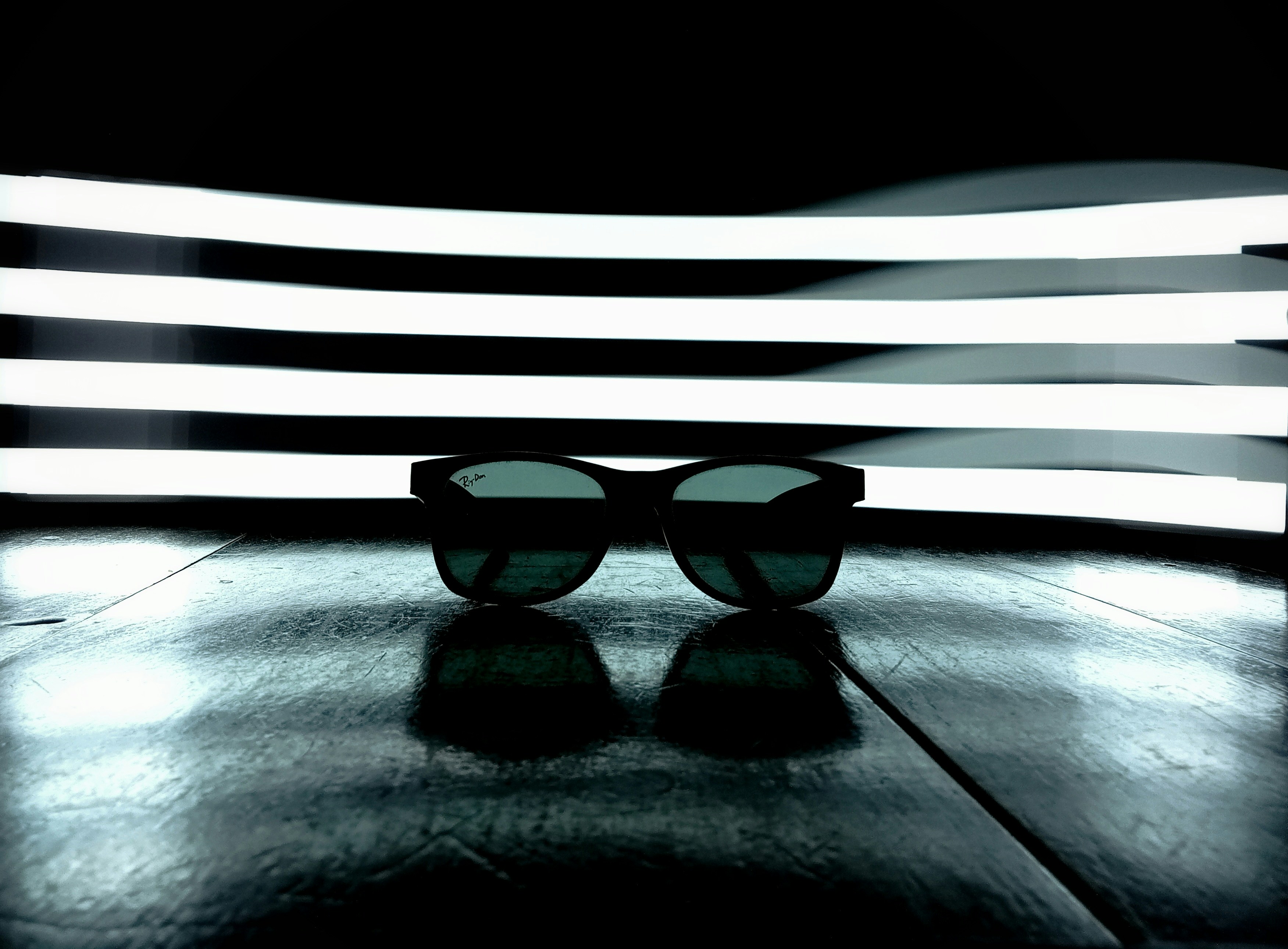 Black wraparound sunglasses on reflective surface with clean studio lighting