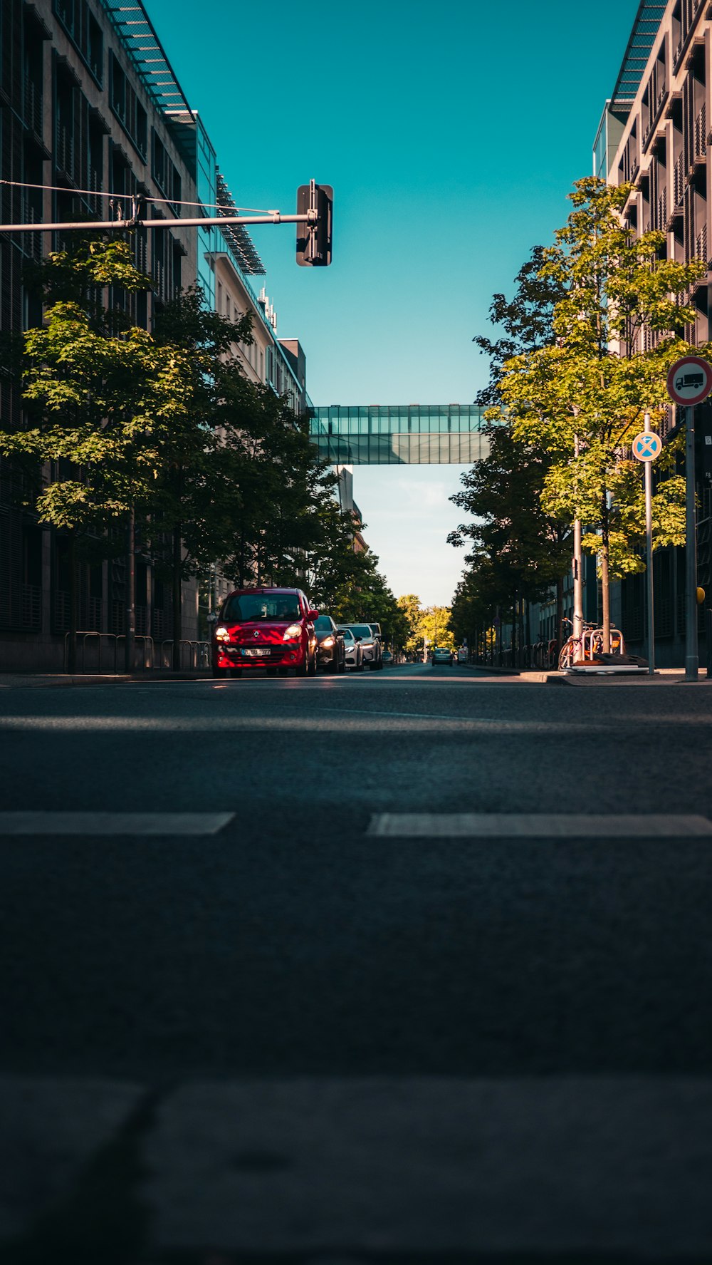 a red car driving down a street next to tall buildings