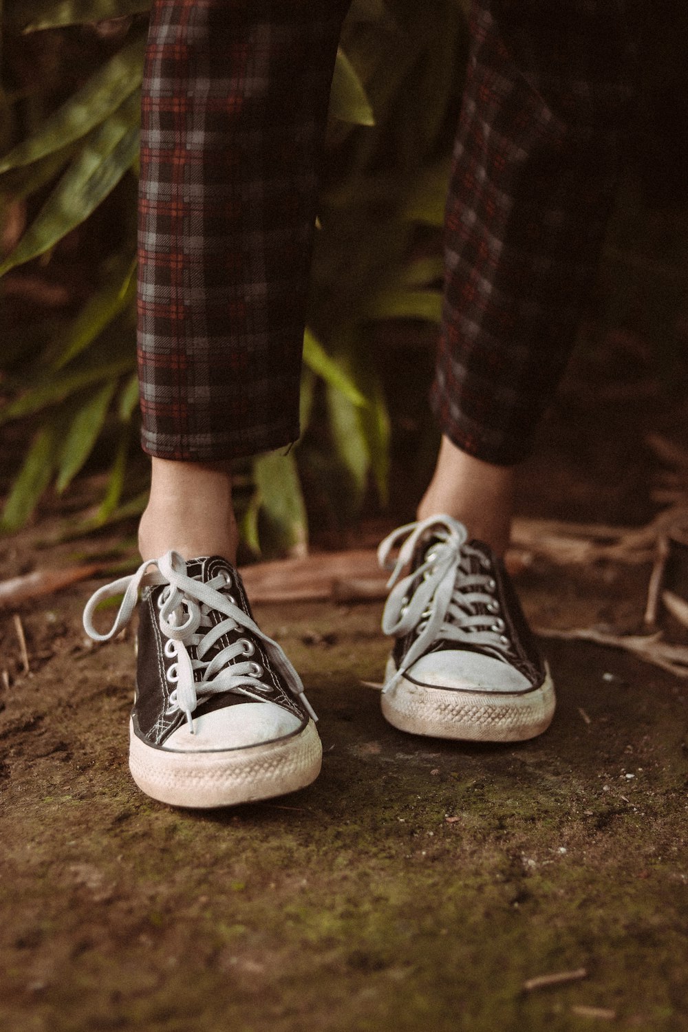 a person wearing black and white sneakers standing on a rock