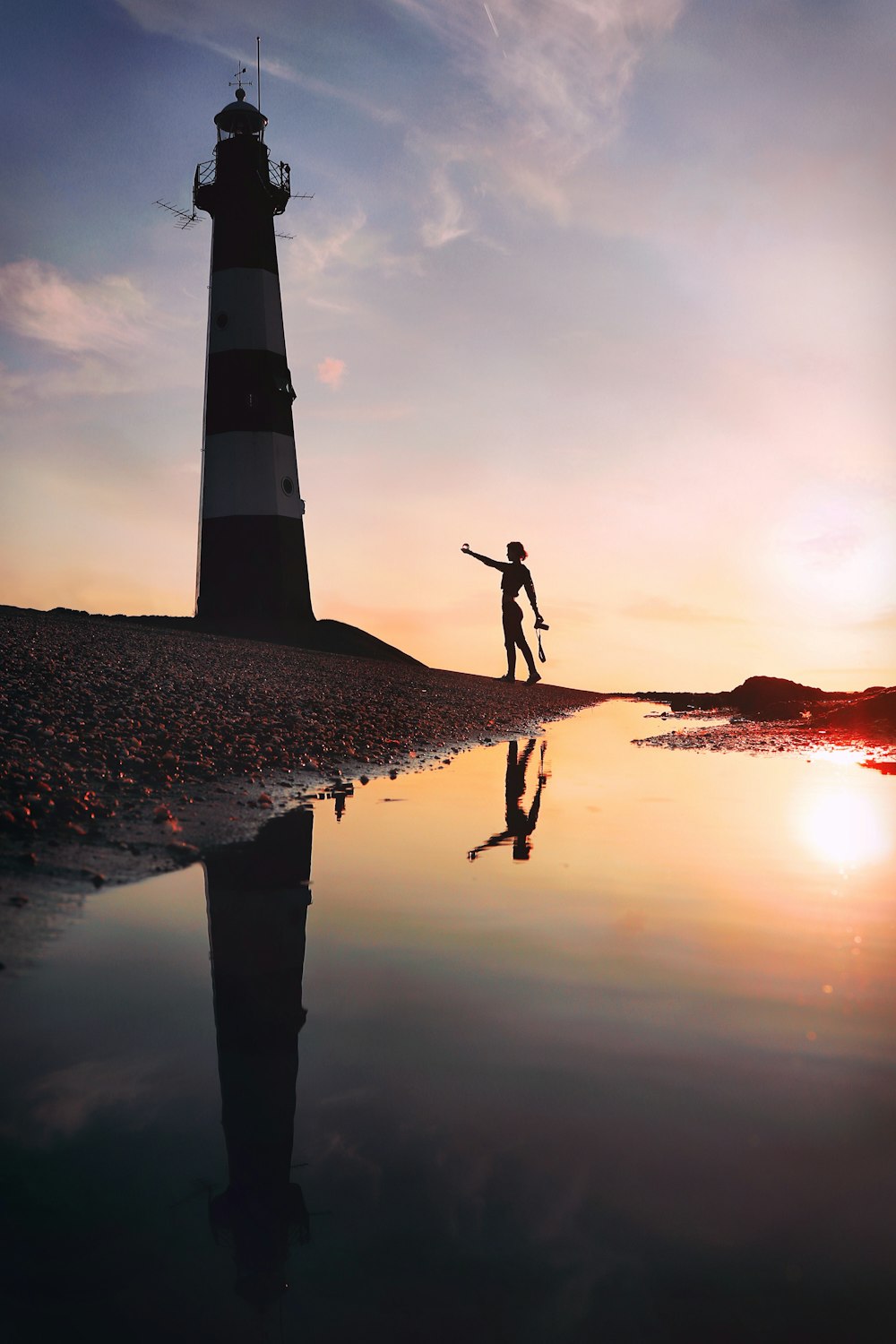 a person standing on a surfboard in front of a lighthouse