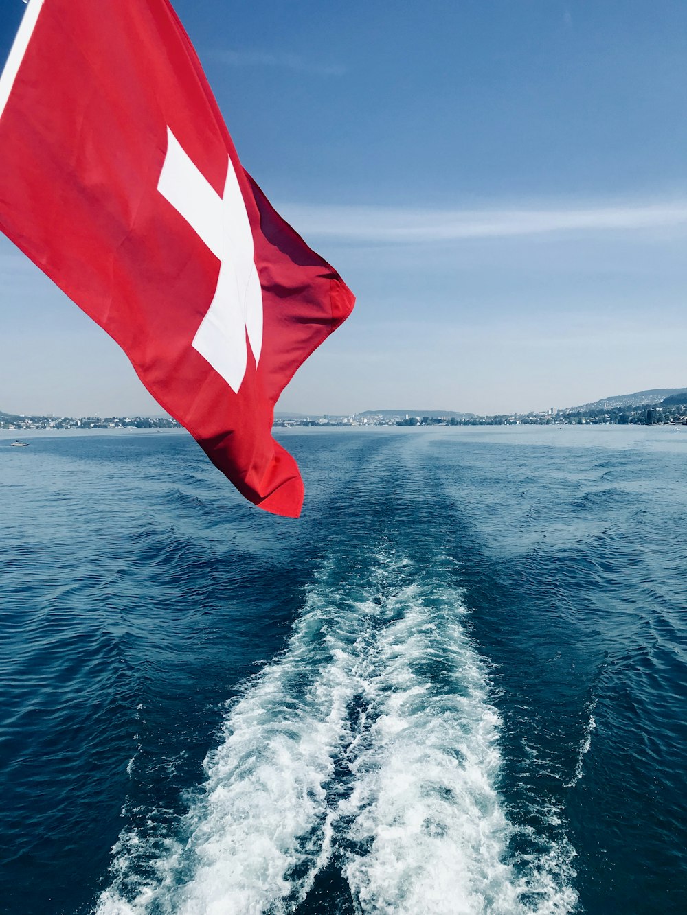 a red and white flag flying from the back of a boat