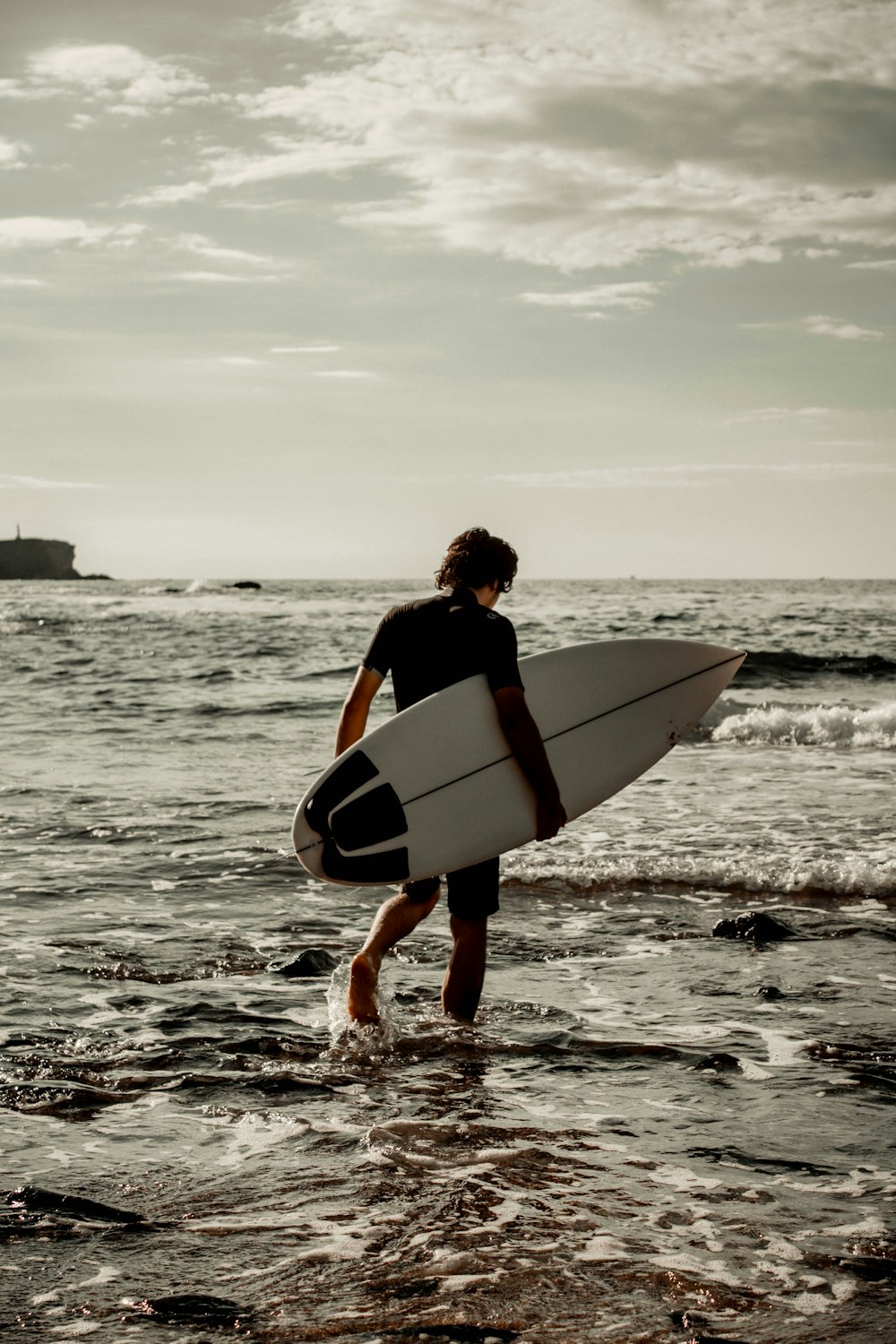 Un uomo che cammina nell'oceano con una tavola da surf
