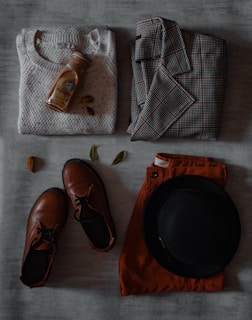 a pair of shoes, a hat, and a sweater laid out on a bed