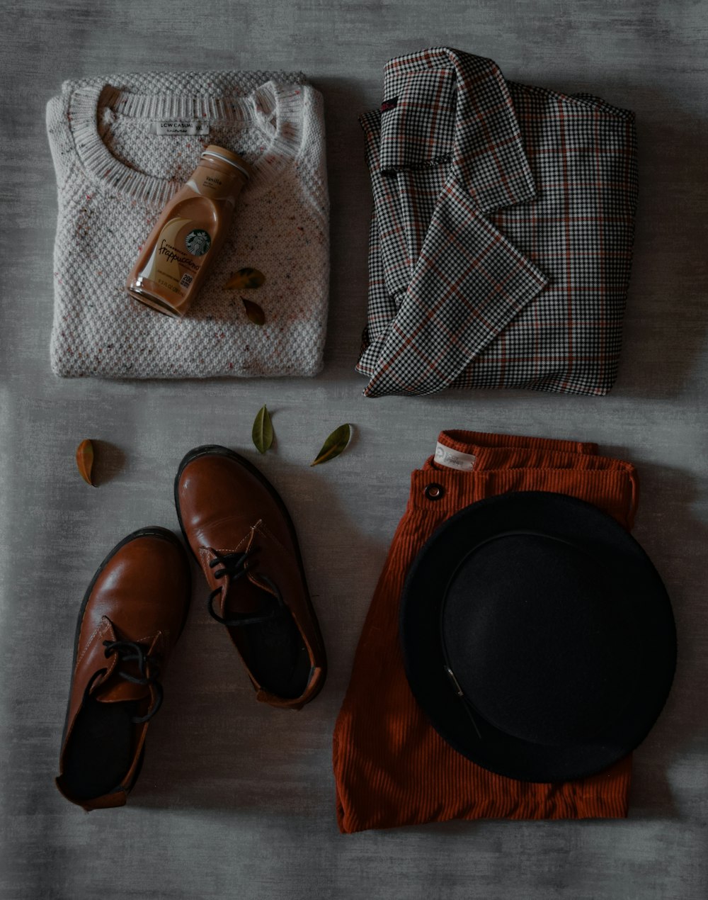 a pair of shoes, a hat, and a sweater laid out on a bed