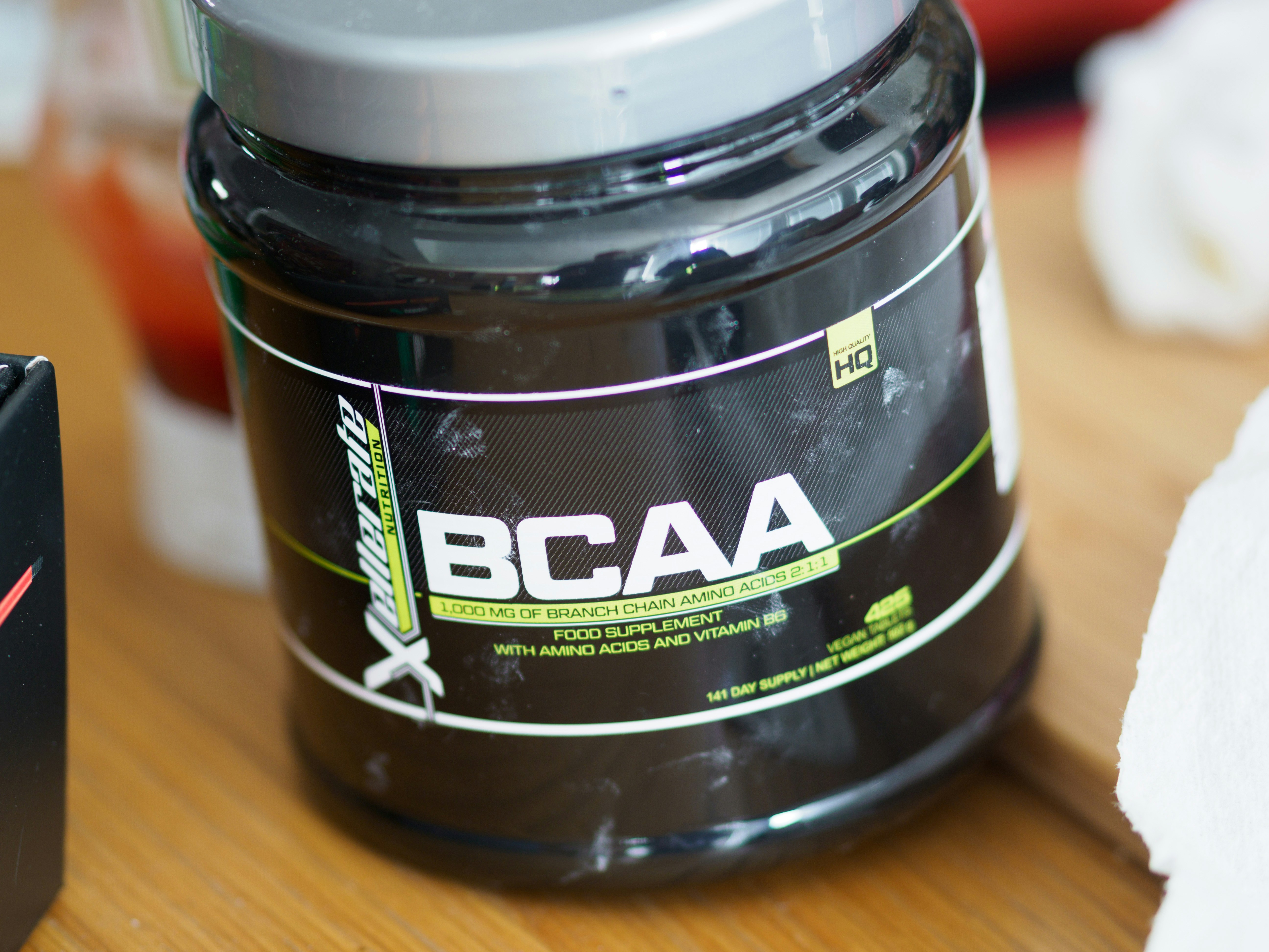 Colorful BCAA supplement bottle with tropical design label, bright gym environment