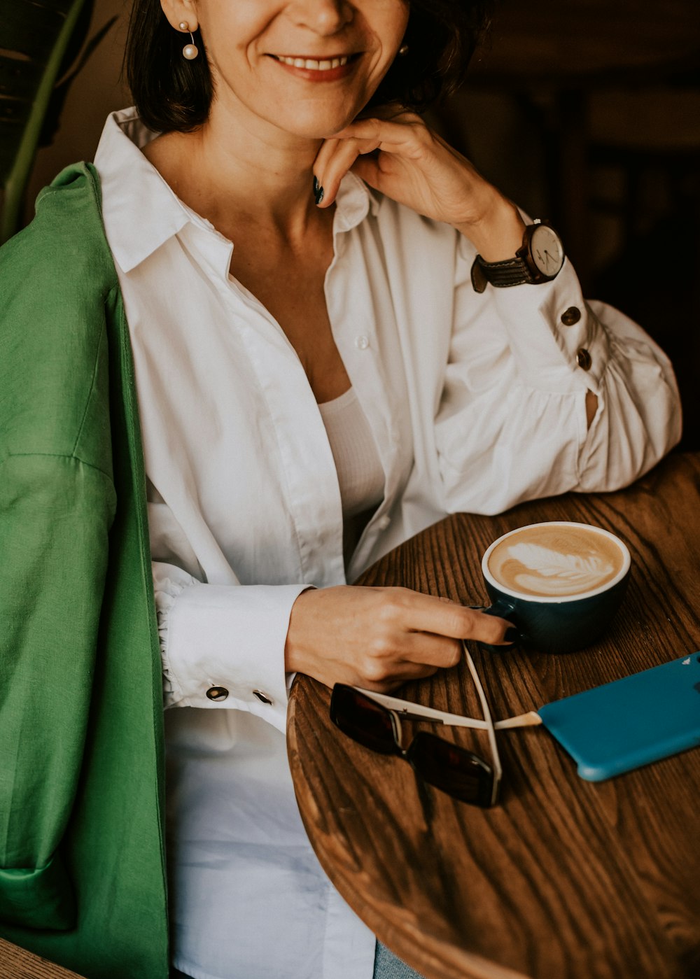 a woman sitting at a table with a cup of coffee