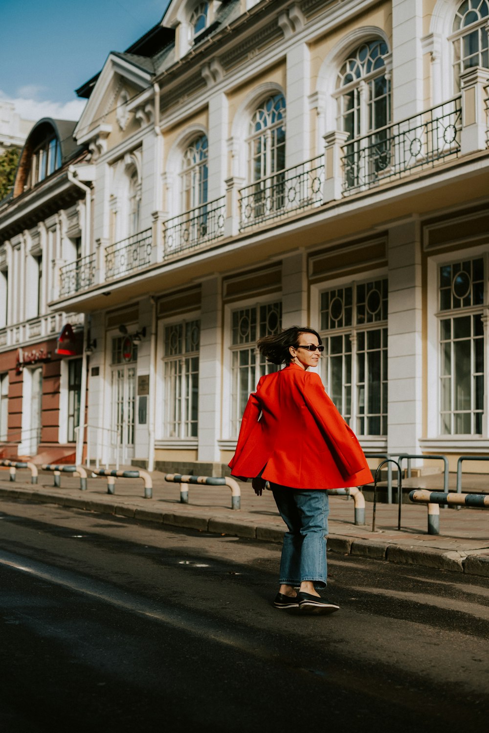 a woman in a red coat is walking down the street