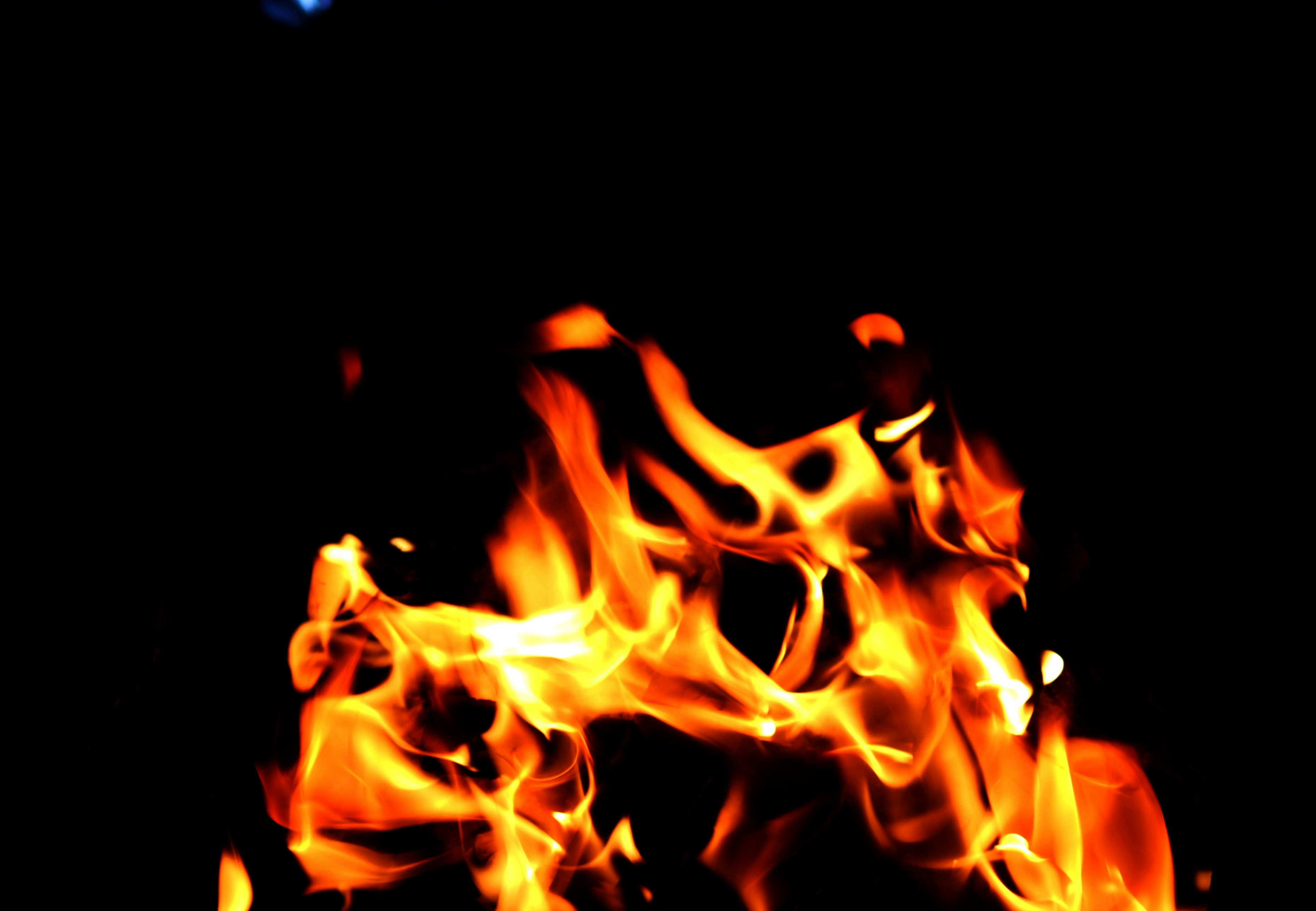 Gece vakti yanan coşkulu bir ateşin etrafında başarıyı kutlayan insanların silüeti; tutku, enerji ve zaferi simgeleyen parlak alevler.