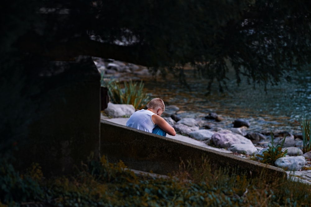 a person sitting on a bench next to a body of water