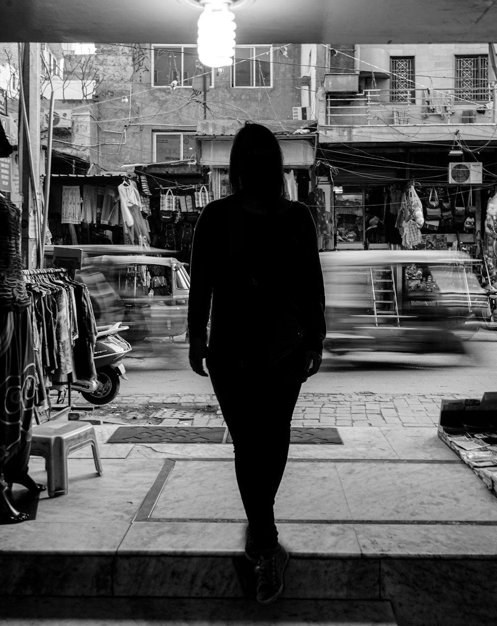 a woman walking down a sidewalk in front of a store