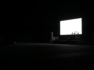 A cozy vintage drive-in theater screen glowing warmly under a clear night sky filled with stars.