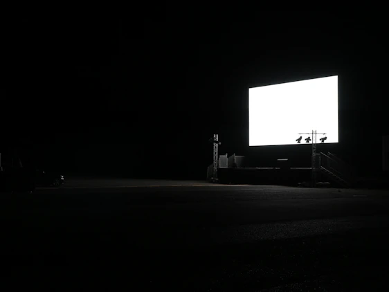 A cozy vintage drive-in theater screen glowing warmly under a clear night sky filled with stars.