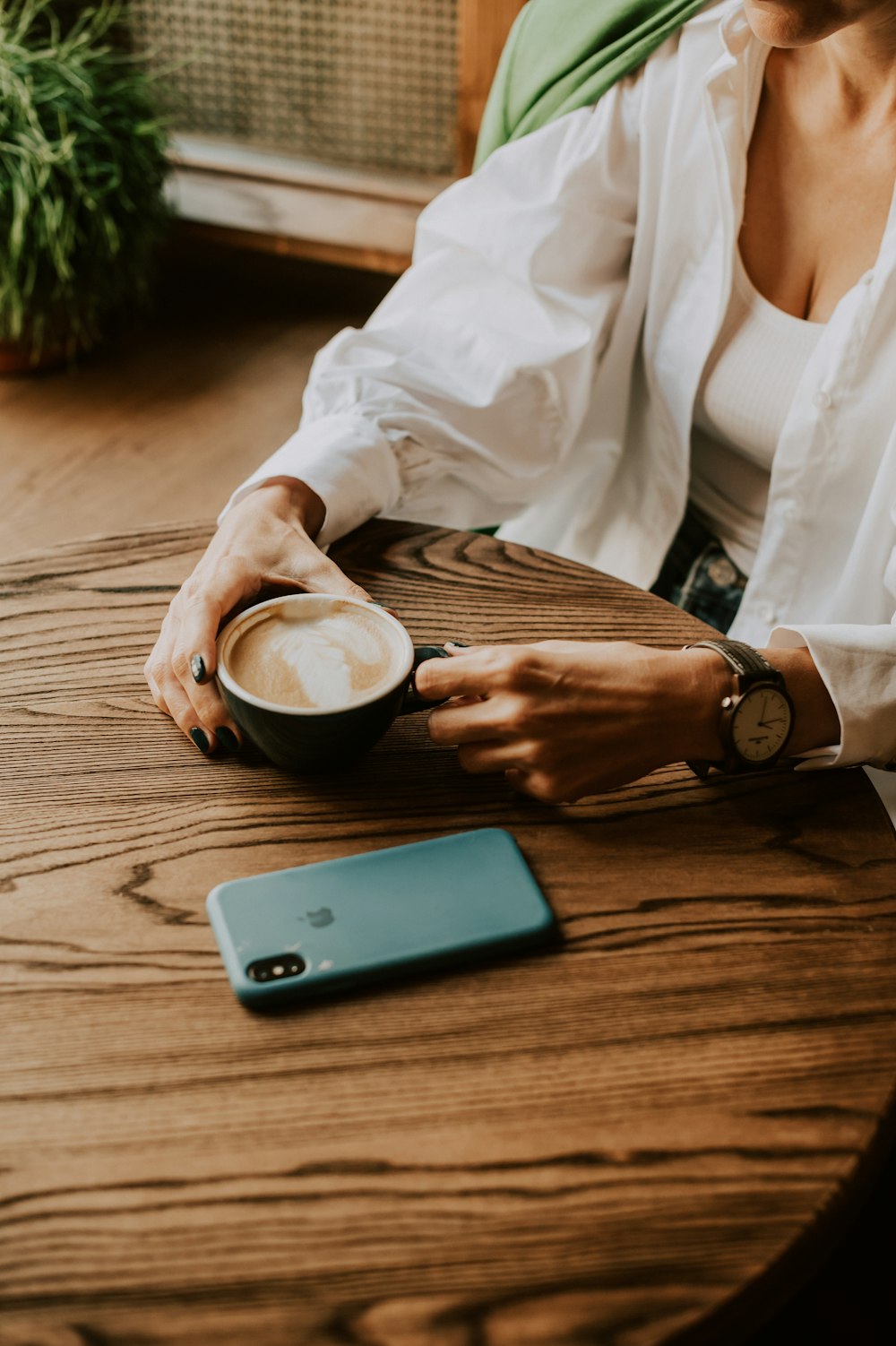 a woman sitting at a table with a cup of coffee