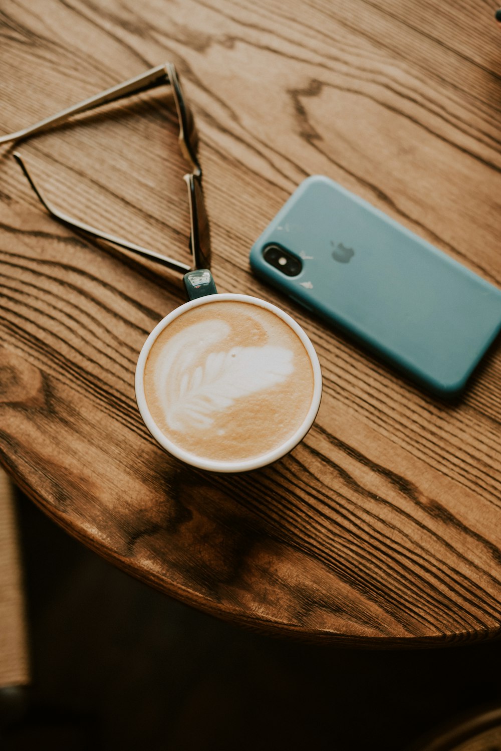 a cup of coffee sitting on top of a wooden table