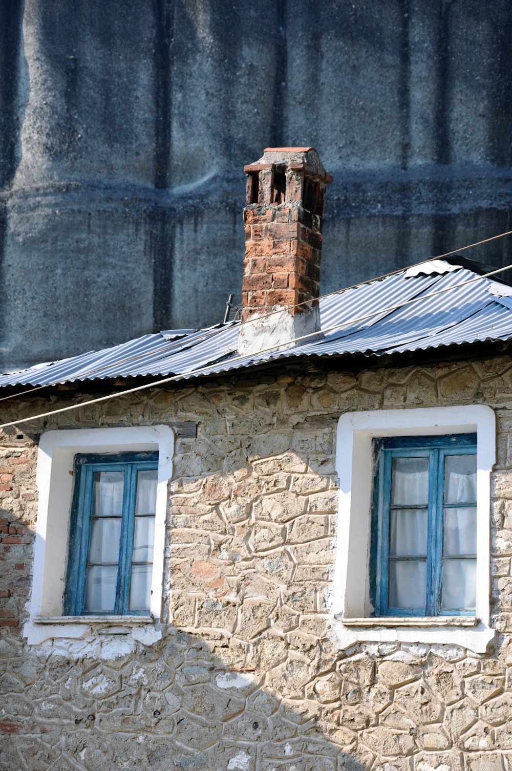 두 개의 창문과 벽돌 굴뚝이있는 석조 건물