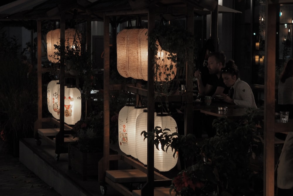 a group of people sitting at a table with paper lanterns
