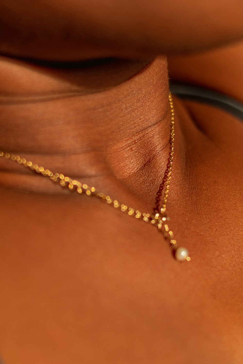 a close up of a person wearing a gold necklace