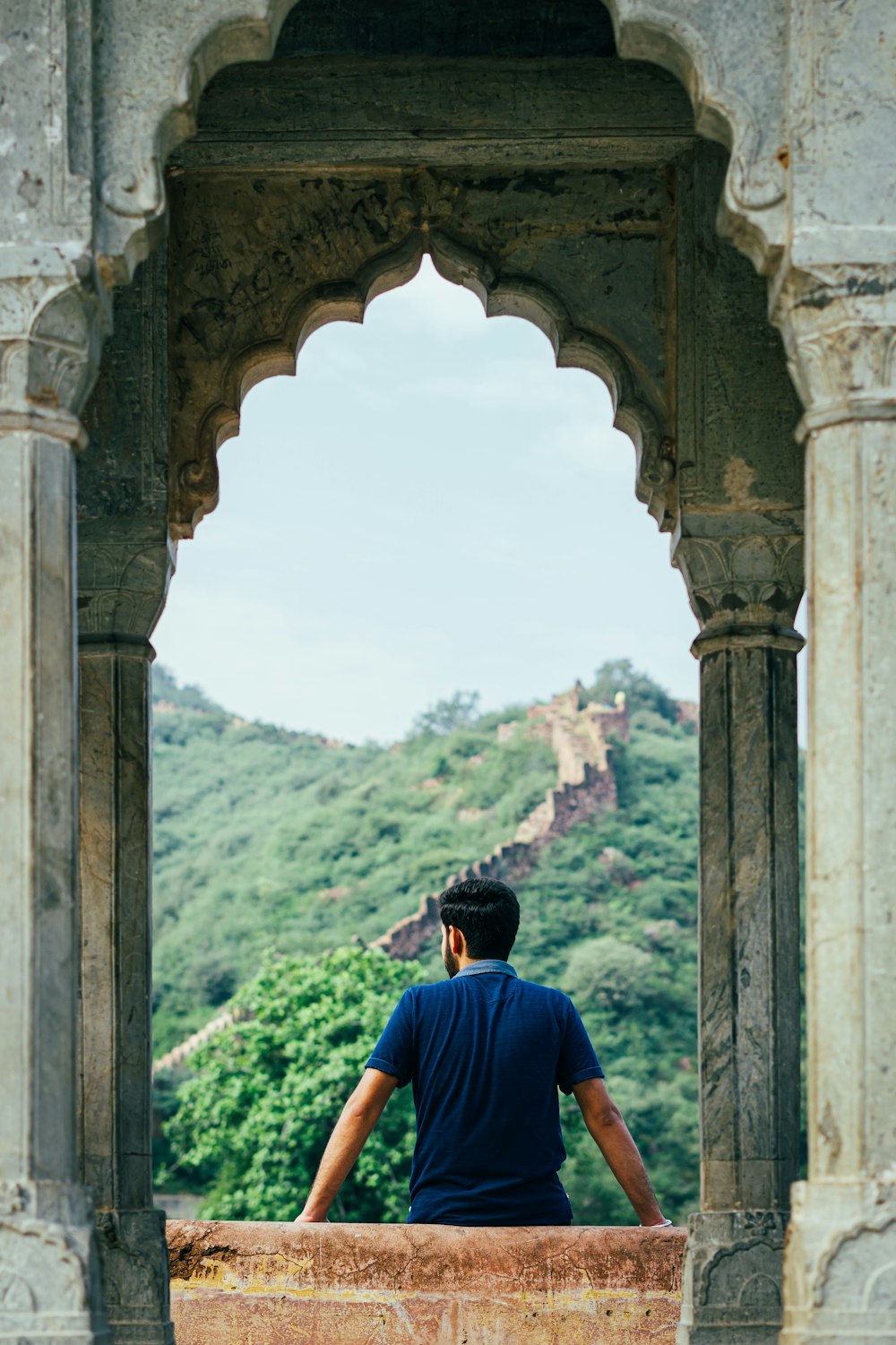 a man sitting on top of a stone wall