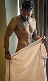 a shirtless man holding a white towel