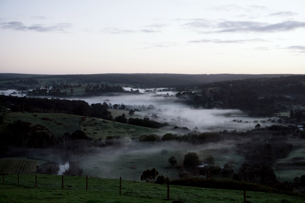 a view of a valley with fog in the air