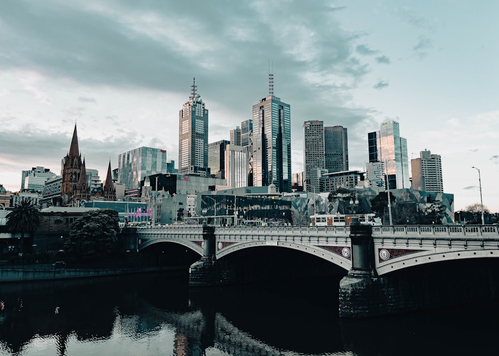 a bridge over a body of water with a city in the background