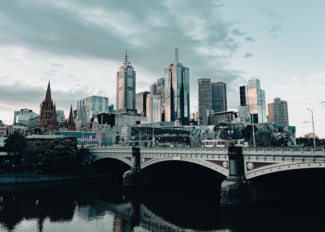 a bridge over a body of water with a city in the background, Melbourne city overlooking the Yarra River. The photo shows