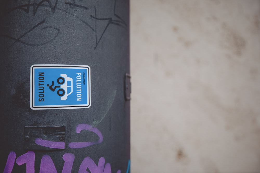 a blue and white sticker on a black pole