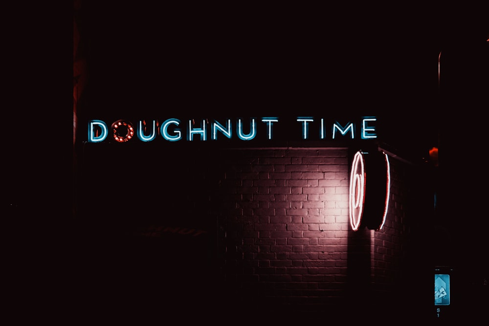 a neon sign that reads doughnut time on a brick wall