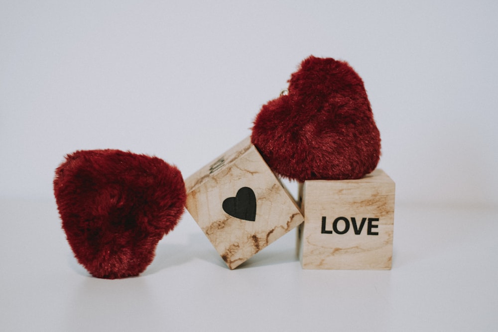 a pair of red hearts sitting on top of a wooden block