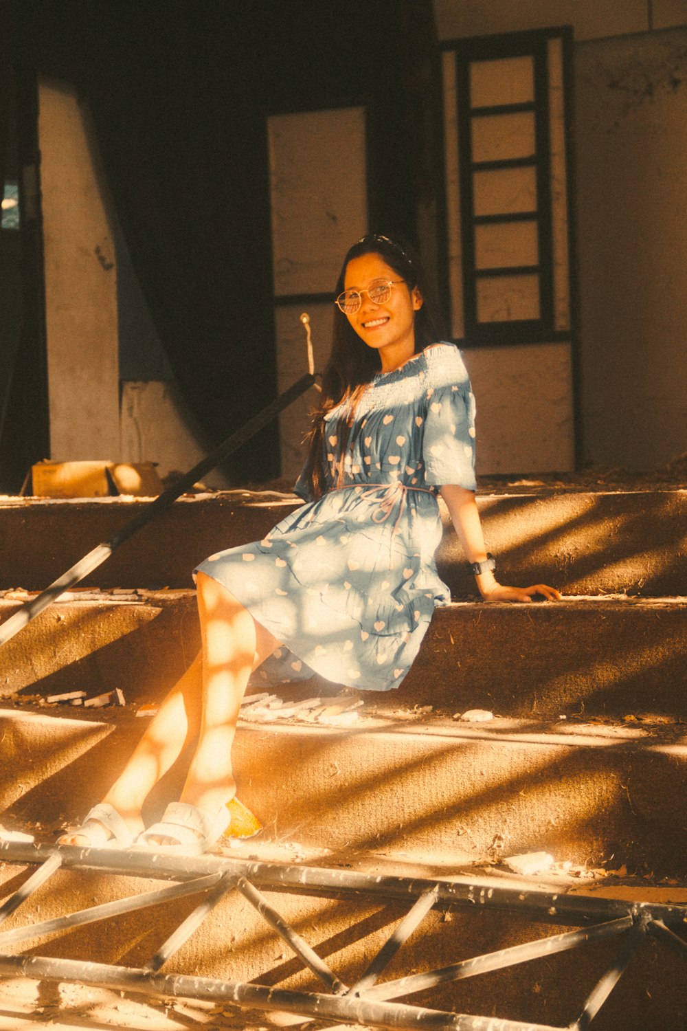 a woman in a blue dress sitting on some stairs