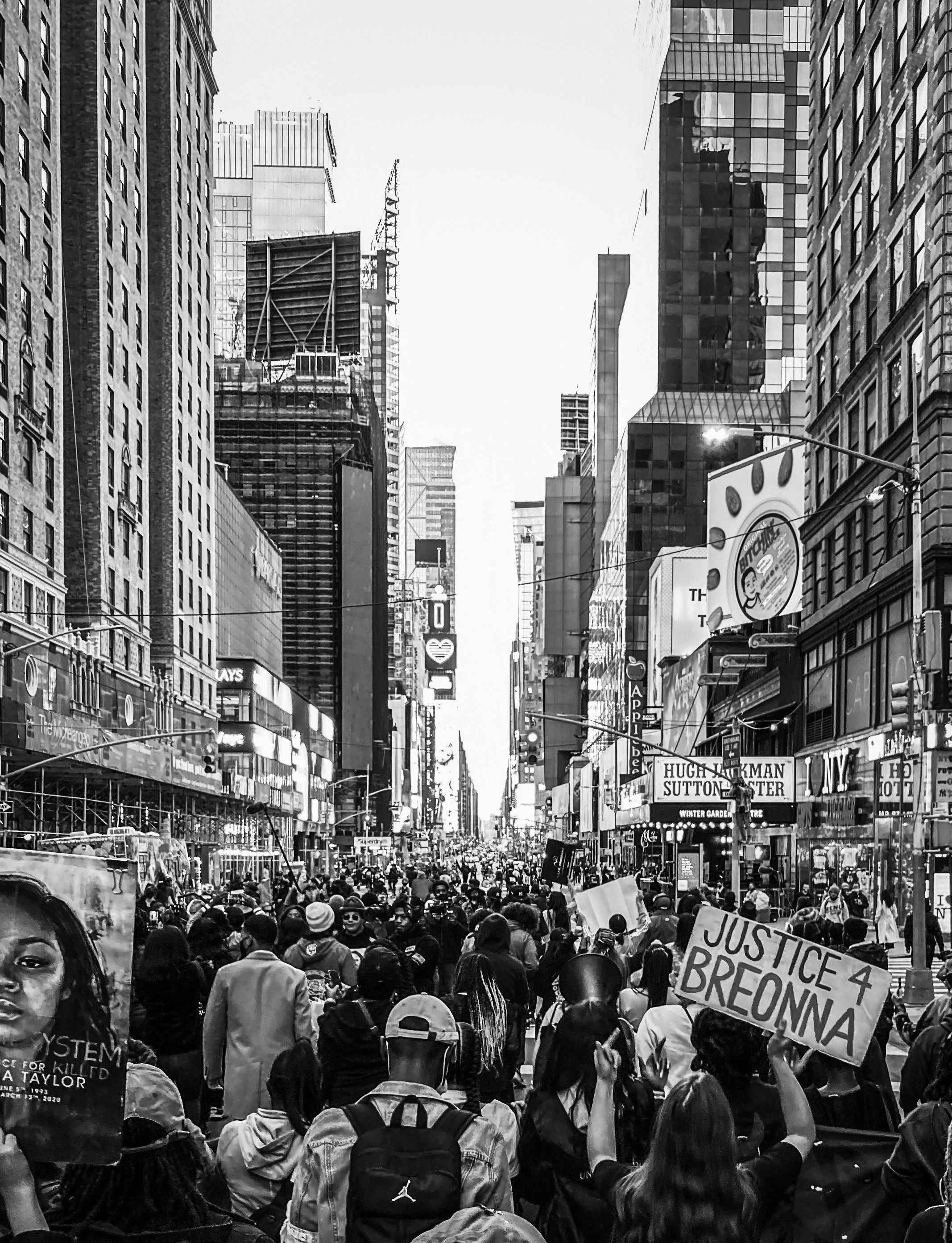 a crowd of people walking down a street next to tall buildings